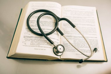 Steteskop ve beyaz zemin üzerine kitaplar.