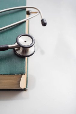 Steteskop ve beyaz zemin üzerine kitaplar.