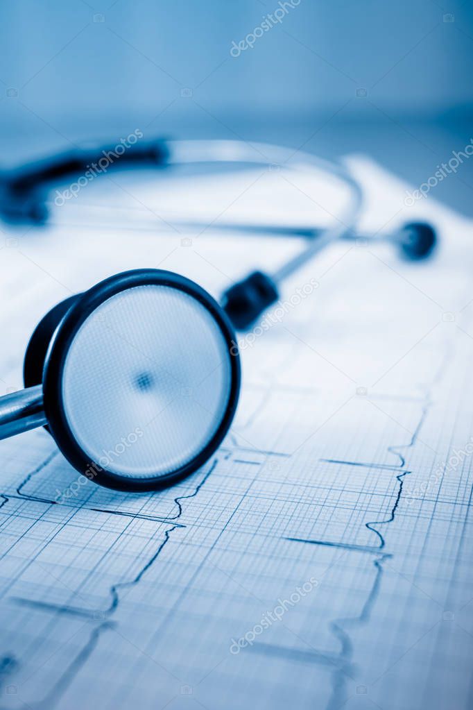 Stethoscope on cardiogram concept for heart care on the desk.blue toned images.