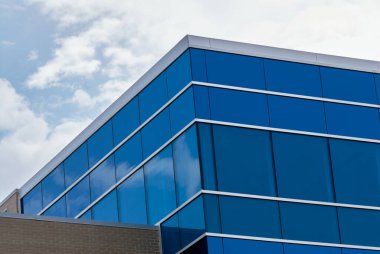 Kanada Saskatoon şehir merkezinde yansıtıcı mavi pencereli modern cam ofis binasının alçak açılı görüntüsü.