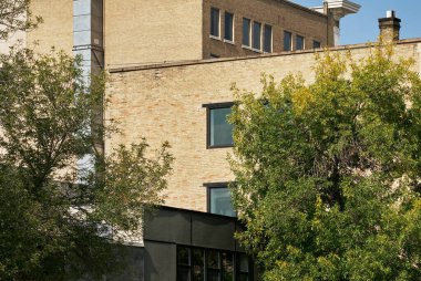 Kanada Saskatoon 'da çekilmiş, yakınlardaki mimariyi yansıtan büyük cam pencereli modern tuğla ofis binasının yan açısı.