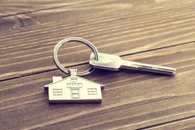 Ev sembollü anahtarlık ve ahşap arka planda anahtarlık, gayrimenkul kavramı