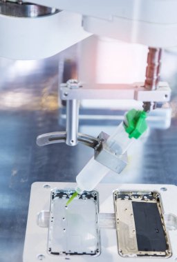 Robot cep telefonu fabrikasına şırınga tutuyor.