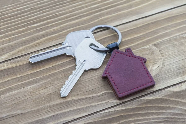 key chain with house symbol and keys on wooden background,Real estate concept