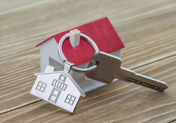 keychain with house symbol and keys on wooden background,Real estate concept