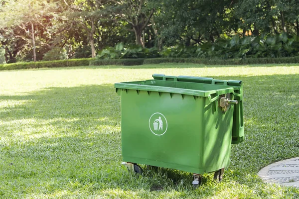 single green trash can (garbage bin) on green grass field in public park