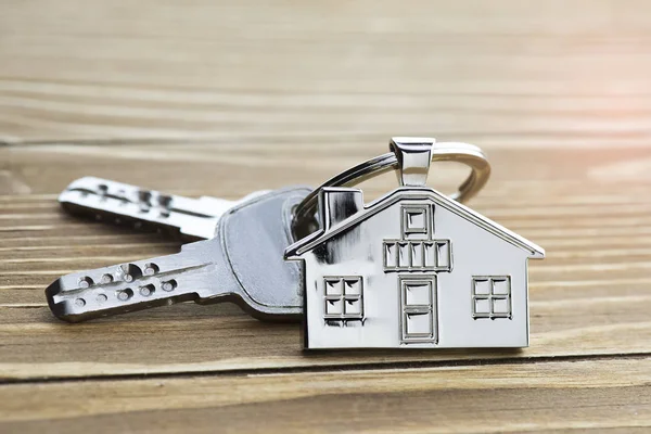 key chain with house symbol and keys on wooden background,Real estate concept