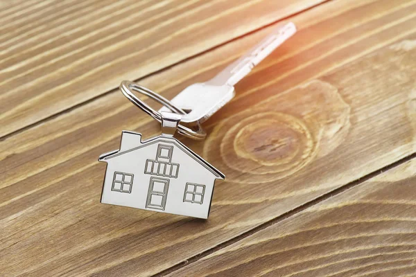 key chain with house symbol and keys on wooden background,Real estate concept