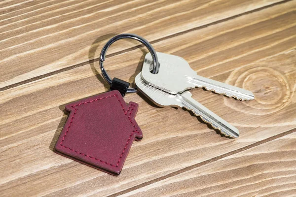 key chain with house symbol and keys on wooden background,Real estate concept