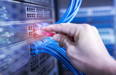 hand plugging red cable in network switch clipart