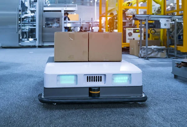 Warehouse robot car carries cardboard box assembly in factory — Stock Photo, Image