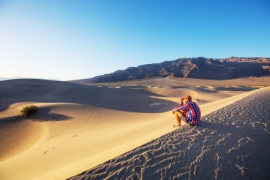 Kum çölünde bir yürüyüşçü. Gün doğumu zamanı.