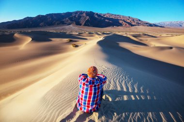 Kum çölünde bir yürüyüşçü. Gün doğumu zamanı.