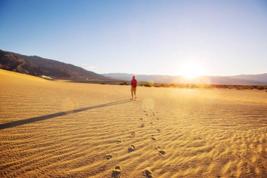 Çöldeki kum tepelerinin arasında bir yürüyüşçü