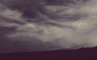 Dağlarda yaz yağmuru. Dramatik bulutlar ve dağların silueti.