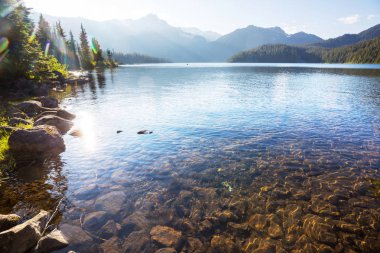 Sakin sulardaki kayaların yansımasıyla dağdaki gölün sakin manzarası..