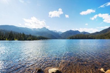 Sakin sulardaki kayaların yansımasıyla dağdaki gölün sakin manzarası..