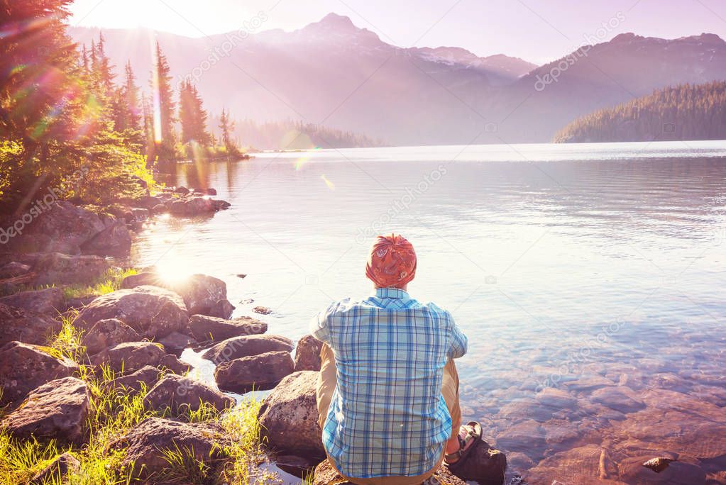 Serene scene by the mountain lake in Canada with reflection of the rocks in the calm water.