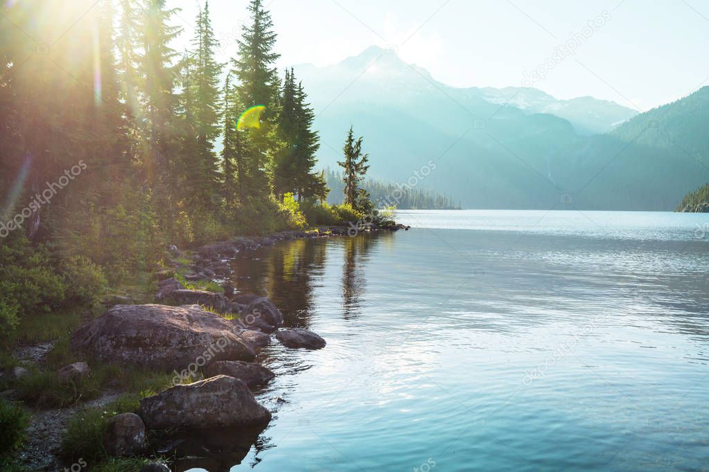 Serene scene by the mountain lake in Canada with reflection of the rocks in the calm water.