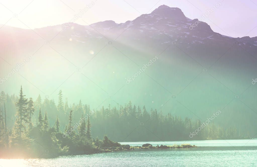 Serene scene by the mountain lake in Canada with reflection of the rocks in the calm water.