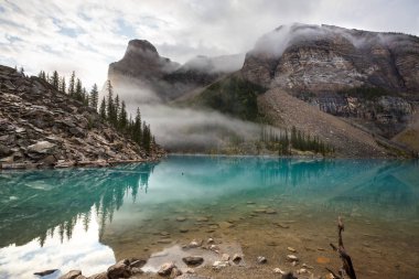 Moraine Gölü 'nün turkuaz suları. Kanada' nın Banff Ulusal Parkı 'nda karla kaplı tepeleri var.