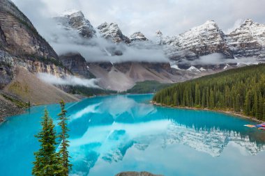 Moraine Gölü 'nün turkuaz suları. Kanada' nın Banff Ulusal Parkı 'nda karla kaplı tepeleri var.