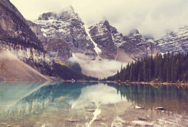 Moraine Gölü 'nün turkuaz suları. Kanada' nın Banff Ulusal Parkı 'nda karla kaplı tepeleri var.