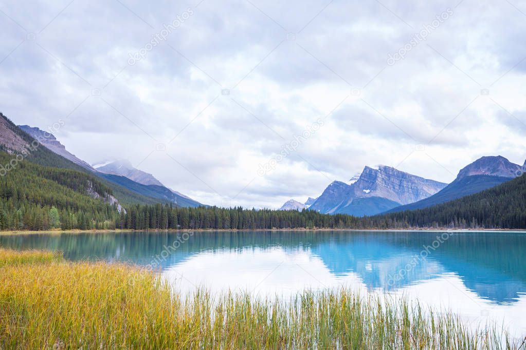 Serene scene by the mountain lake in Canada with reflection of the rocks in the calm water.