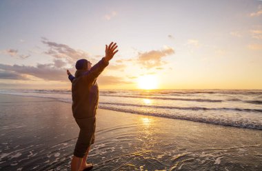 Mutlu adam gün batımında okyanus sahilinde