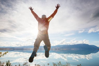 Sakin gölün üzerinde zıplayan adam