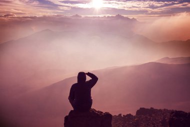 Dağda oturan adamın silueti, ilham konsepti sahnesi.