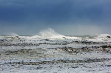 Kumsalda mavi dalga. Bulanık arkaplan ve güneş ışığı lekeleri. Dramatik doğal arka plan.