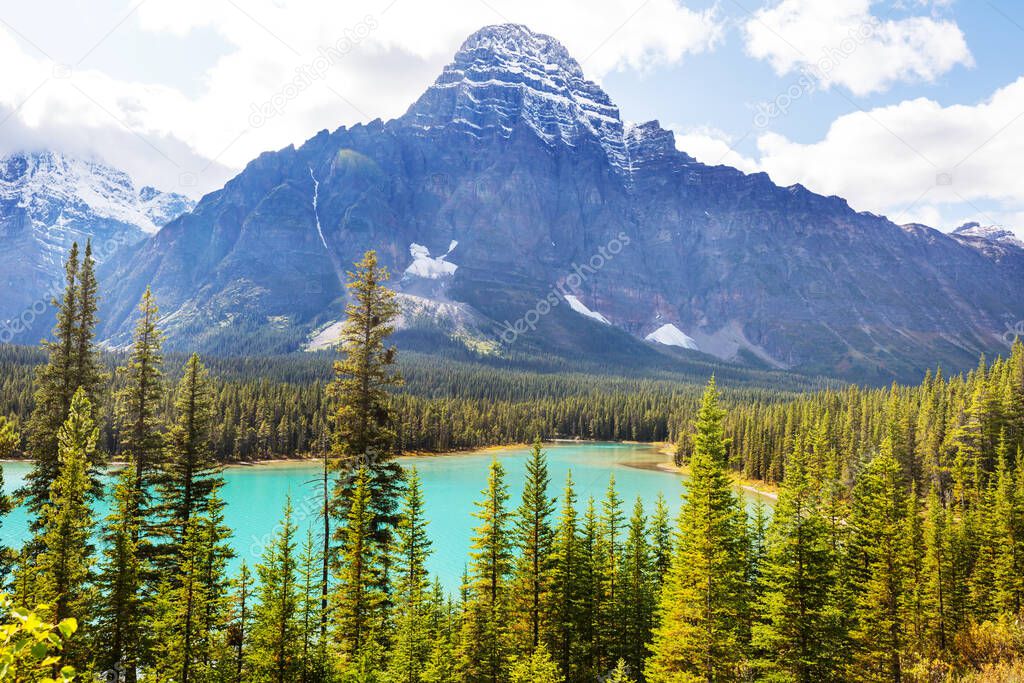 Serene scene by the mountain lake in Canada with reflection of the rocks in the calm water.