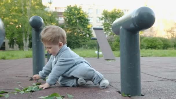 Entzückend lustiges Babyspiel auf dem Spielplatz unter der Obhut seiner Hipster-Eltern — Stockvideo
