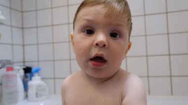 Kahverengi gözlü bebek bebek çocuk ailesinin yardımıyla küvet yıkama