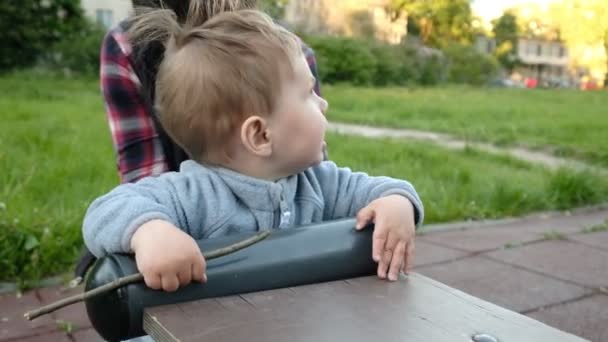 Schattig grappige baby spelen in Speeltuin onder zorg van zijn ouders hipster — Stockvideo