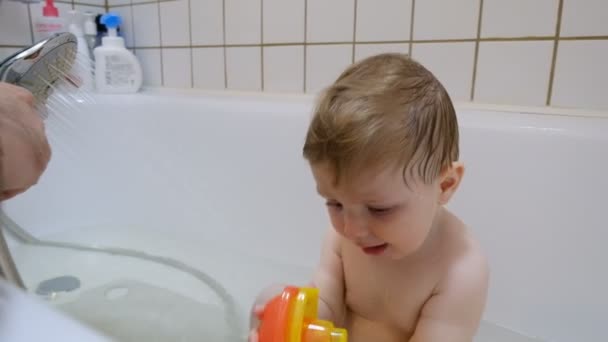 Rozkošný hnědooká kojenecká baby boy mytí ve vaně s pomocí svých rodičů — Stock video