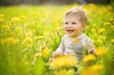 Konsept: aile değerleri. Güneşli dandelions alanında açık oynayan ve komik surat masum kahverengi gözlü Bebek portresi.