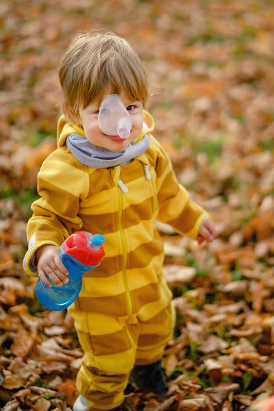 Šťastný chlapeček s lahví na podzim, který si hraje v parku při procházce. — Stock fotografie