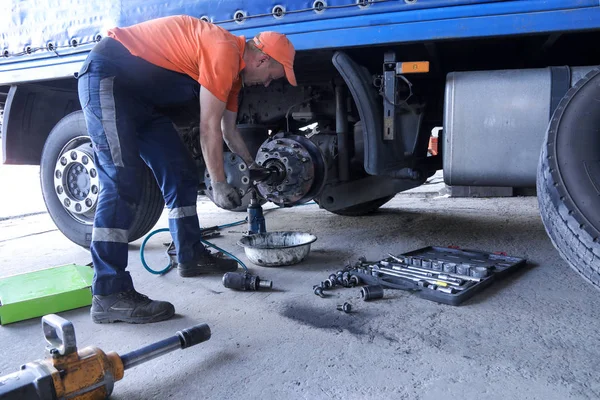 Two mechanic repairs a truck. Replace brake disc and pads