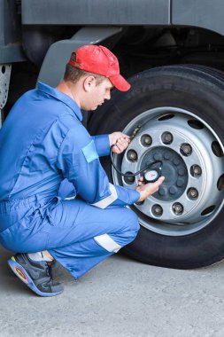 Bir tamirci lastik basıncını ölçer.