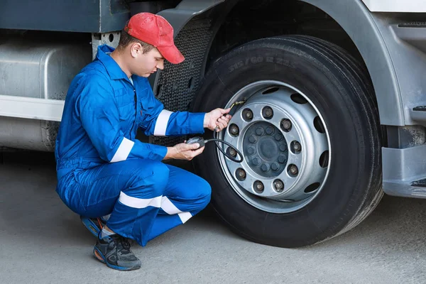 A mechanic checks the tire pressure gauge truck