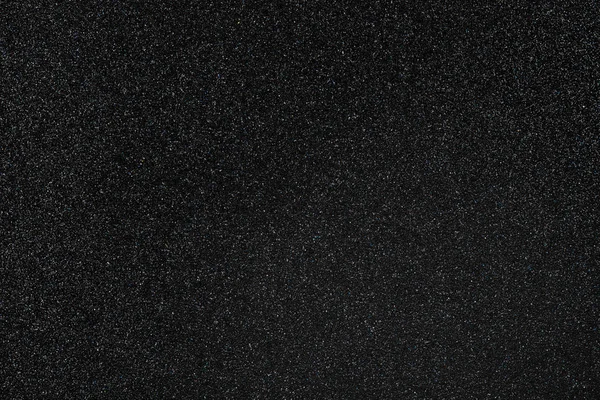 Coal black colored sand paper textured background with sparkles and glitters