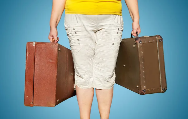 A woman in a yellow T-shirt stands with suitcases in her hands. — Stock Photo, Image