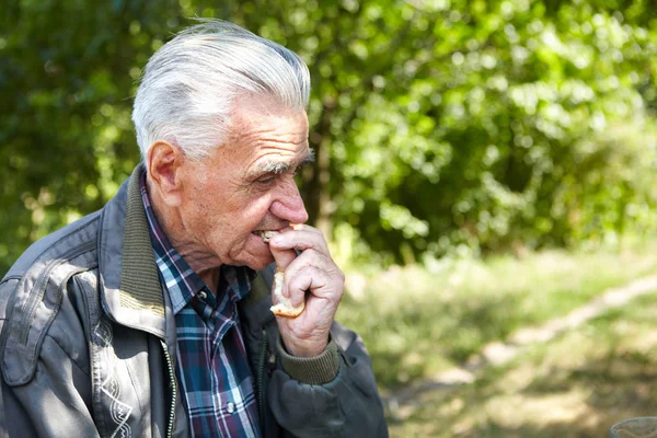 Elderly poor man eating bread — Stock Photo, Image