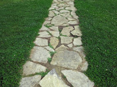 Taş tuğla geçit aracılığıyla yeşil çim çimen döşeli