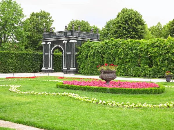 Abstract black garden arbor, flower beds and shorn trees in a well-kept park