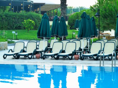 Eğlence için bir yüzme havuzunun su önünde şezlonglar.