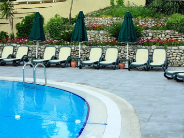 Eğlence için bir yüzme havuzunun su önünde şezlonglar.