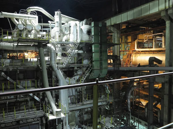 Pipes, steel tubes, steam turbine and equipment at industrial power plant, night scene